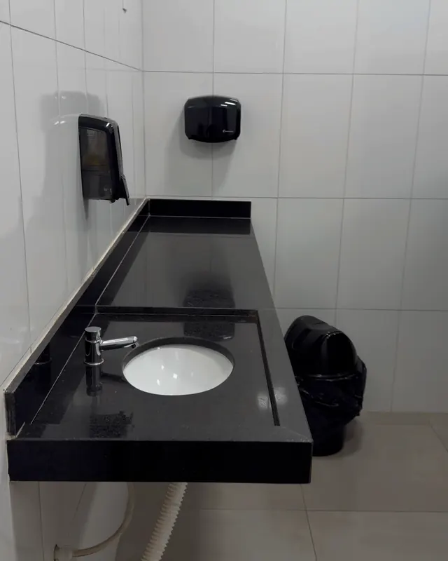 Banheiro acessível: lavatório em bancada de granito, com secador de mãos e saboneteira.