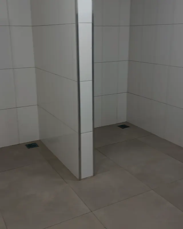 Vestiário: boxes de chuveiro revestidos de azulejo branco, com ralo no piso.