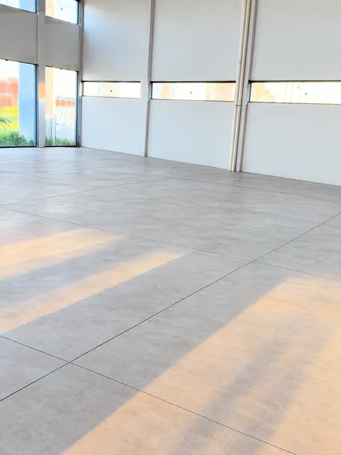 Espaço atual: interior vazio do salão, piso de concreto e janelas altas (foto com tratamento digital)